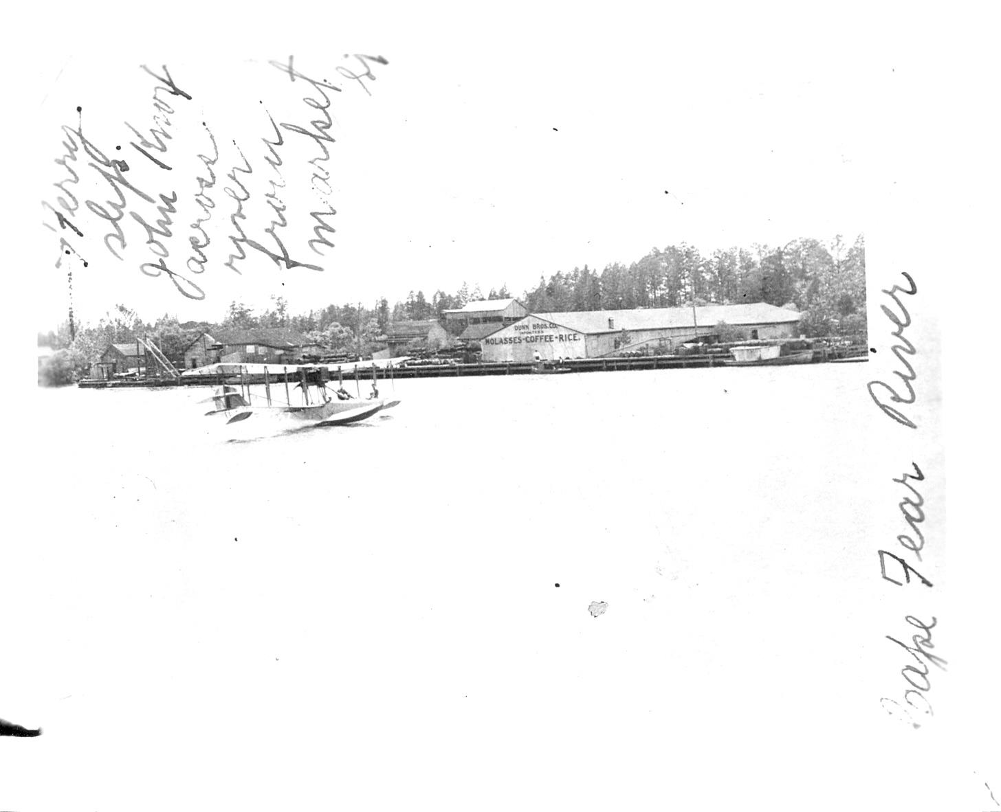 Historic photograph of a seaplane on the Cape Fear River in front of the Dunn Brothers warehouse on Eagles Island